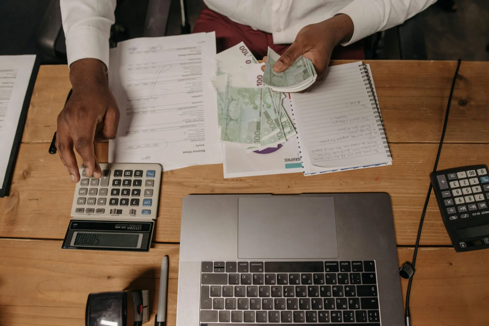 Desk with calculators, documents and a laptop