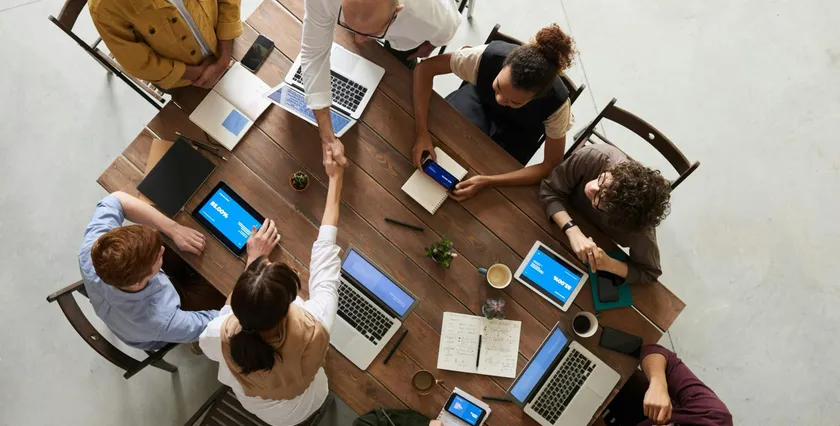 Team collaborating around a table with laptops