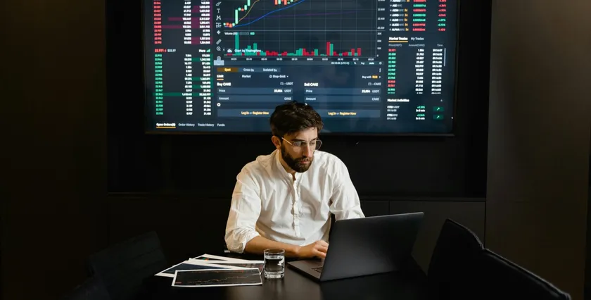 Person working at a screen-lit trading desk