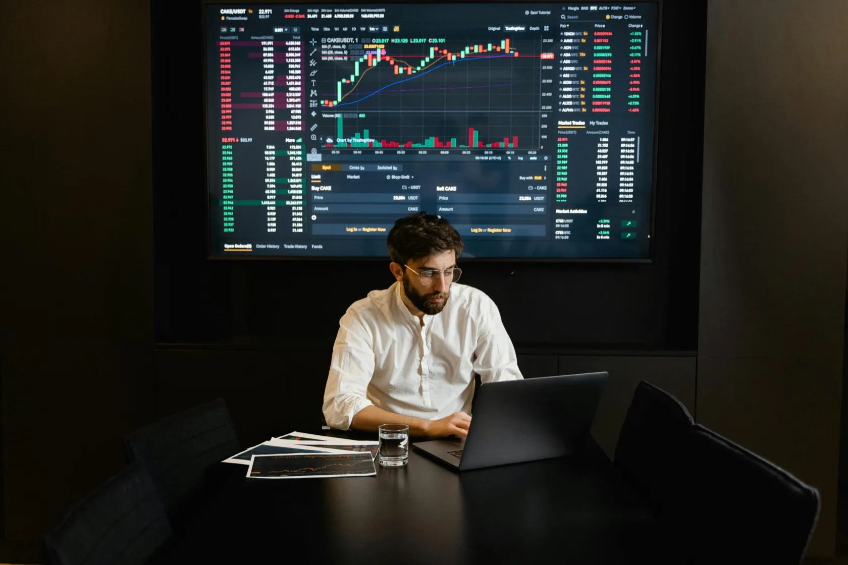 Person working at a screen-lit trading desk