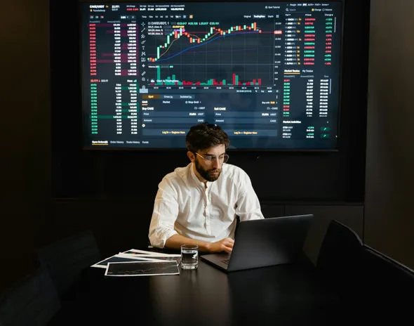 Person working at a screen-lit trading desk