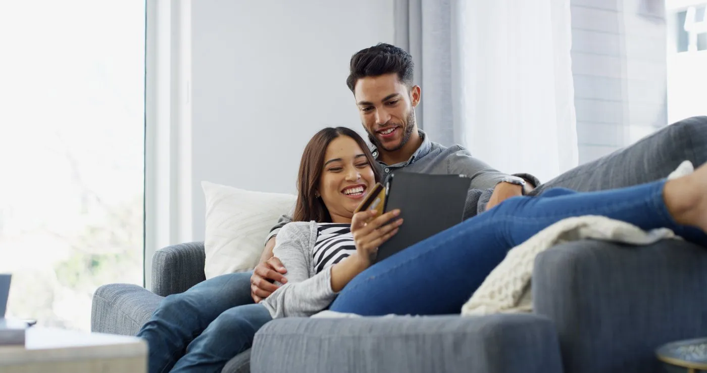 A couple relaxing on a sofa looking at a tablet together