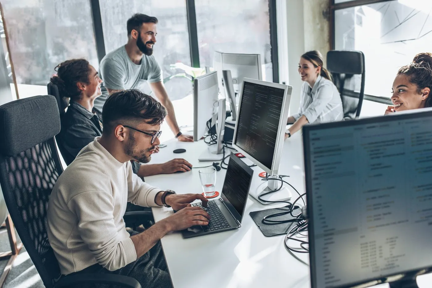 A product team working across desks of monitors in an open office