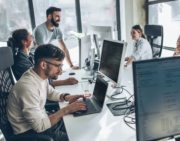 A product team working across desks of monitors in an open office