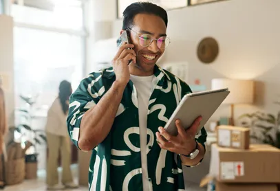 A shop owner on the phone holding a tablet in their store