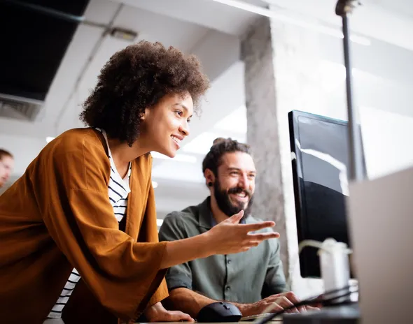 Two colleagues looking at a monitor together at a desk