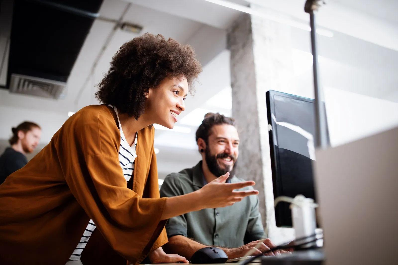 Two colleagues looking at a monitor together at a desk